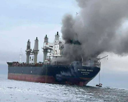An oil tanker with thick grey smoke billowing from its stern