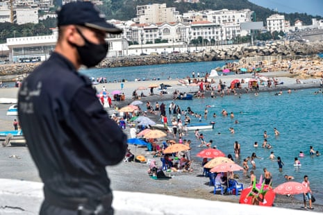 A mask-clad policeman watches as people cool off in the water at el-Kettani beach in the Bab el-Oued suburb of Algeria’s capital, Algiers, on 15 August, 2020, as the country eases pandemic restrictions.