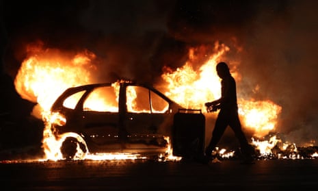 A protester walks by a burning car during clashes with police in Le Port, on the French Indian Ocean island of La Reunion.