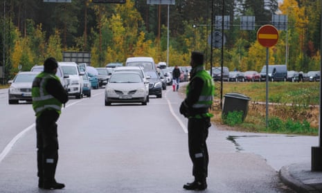 Finnish border guards look at cars queueing at the Vaalimaa border crossing between Finland and Russia