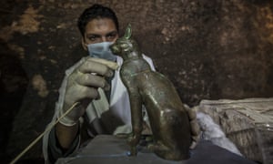 An archaeologist cleans a ancient cat statue
