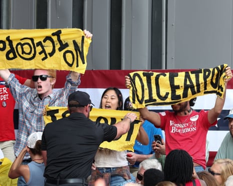 A security guard pulls down a protester’s yellow banner at a Trump campaign rally in Georgia