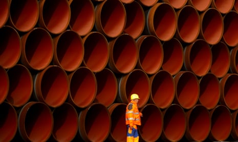 A worker walks in front of stacked pipe sections