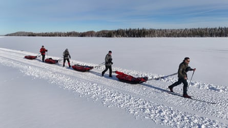 Military veterans crossing a snowfield, each towing a sled