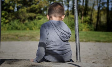 A child at a playground looking down at the ground