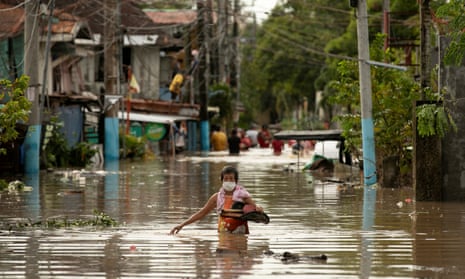 A resident wades through waist-deep floodwaters in San Miguel, Bulacan province, after Super Typhoon Noru hit the Philippines.