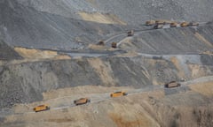 Series of trucks driving along a winding road at an open-pit copper mine