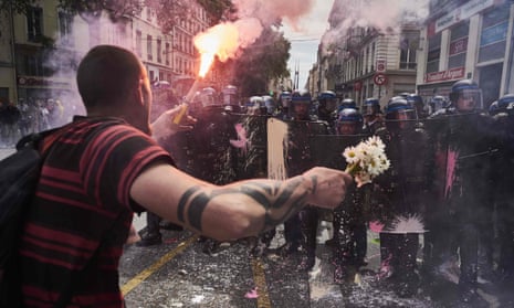 A man holds a bouquet of flowers and a torch as he faces riot police during a demonstration in Lyon, central eastern France. 