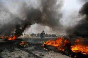 A demonstrator moves burning tyres during anti-government protests in Basra, Iraq