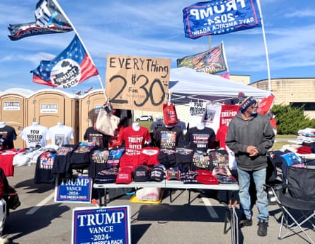 shirts on a table next to man wearing grey sweater and blue jeans
