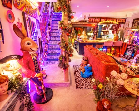 The living room of a house that is a blaze of neon pinks and reds, with a giant rabbit statue, animal prints and knick-knacks