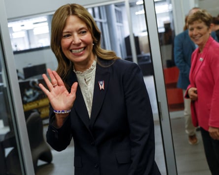 Amy Acton, Ohio gubernatorial candidate, smiles and waves while walking through a glass doorway