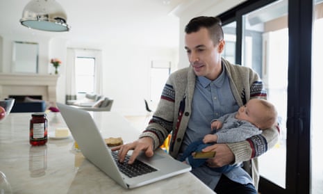 Father holding baby son and working at laptop