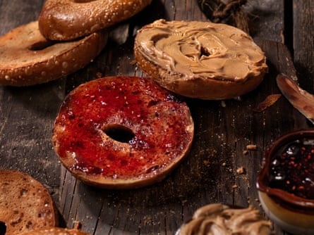 Half a bagel spread with peanut butter and another half spread with red jam