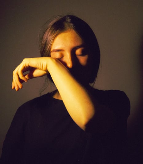 A young woman in a black sweater wipes a tear from her eye with the back of her wrist