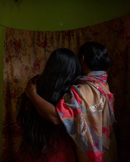 A woman in a shawl hugs a girl, both with their backs to the camera