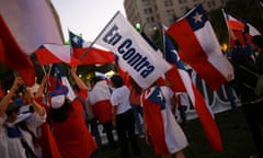 A person holds a flag that reads ‘against’ as voters take part in a referendum on a new Chilean constitution, in Santiago, Chile