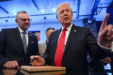 a man in a suit holds up his left index finger while holding a pen with his right hand