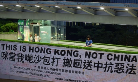 An activist ties a banner that reads ‘This is Hong Kong, not China’ to a pedestrian bridge leading to the Legislative Council in Hong Kong