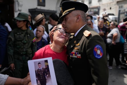 A military officer comforts Ramona Palma who is crying as a person holds up a photo of a soldier