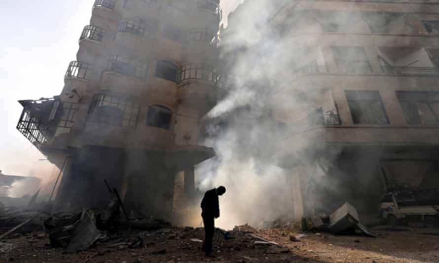A man walks in front of a burning building after a Syrian air force strike in Damascus.