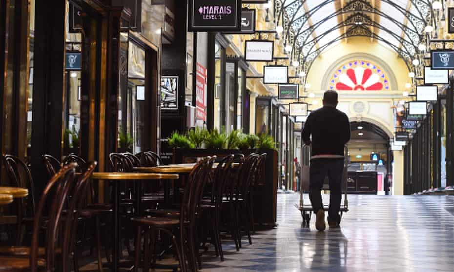 A man pushes a trolley past empty chairs and tables in Melbourne’s normally bustling city centre