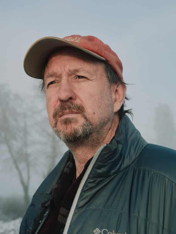 A man with a beard and a red cap looks leftwards