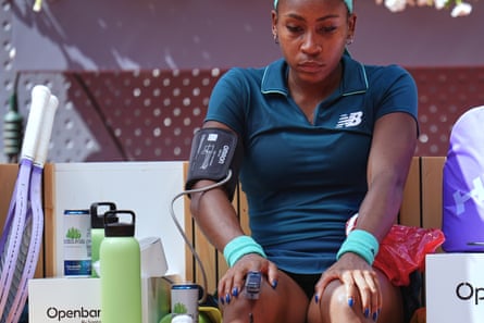 Coco Gauff sits on court with a blood pressure monitor on her arm and medical device on her finger
