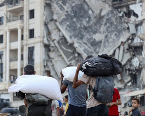 Palestinians carry aid supplies after trucks loaded with aid entered from Israel through central Gaza, in Gaza City on 22 July 2025.|465x371.9426456984274