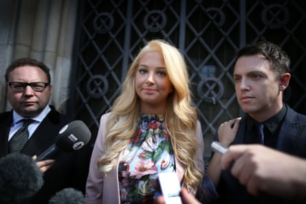 A blond woman with two men, either side,