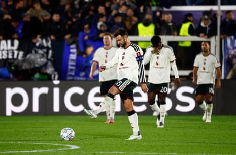Bruno Fernandes kicks the ball as dejected Manchester United teammates walk behind him