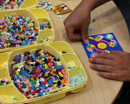 A pair of hands putting together a mosaic from a tray of bricks.