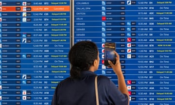 A woman takes a picture of a flight tracking board that reports delays for more than half the flights