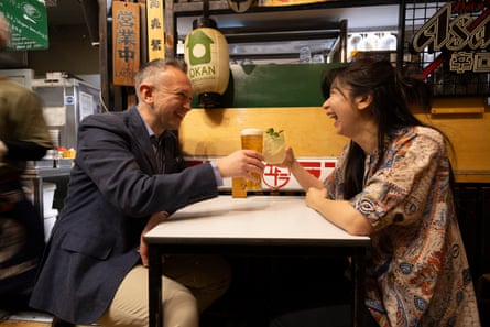 David and Yung Yung talking clinking glasses and smiling while sitting opposite each other at a restaurant table