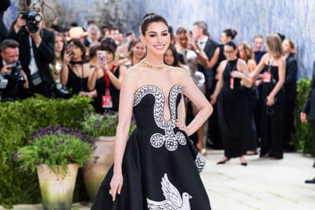 A woman in a gown smiles for photographers during a red carpet event