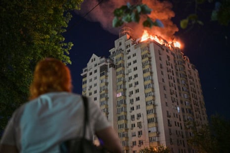 A woman looks at an apartment building burning after a Russian missile attack
