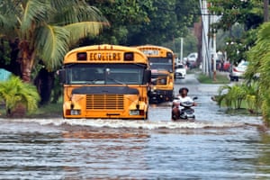 School buses pass through a flooded street