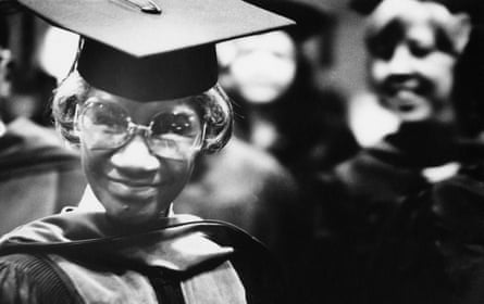 Woman with glasses smiles in graduation cap