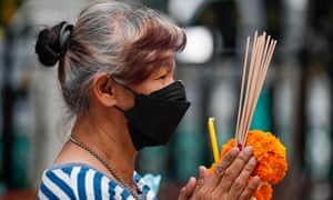 A woman wearing a protective face mask prays at a shrine in Bangkok, Thailand, as the country reports its first domestic cluster of coronavirus infections from the Omicron variant.