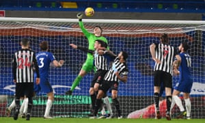 Kepa Arrizabalaga of Chelsea punches the ball clear under pressure from Ciaran Clark and Jamaal Lascelles of Newcastle United.