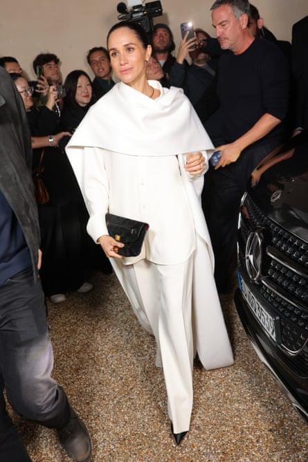 Meghan, Duchess of Sussex, in a white trouser suit with a white wraparound shawl.