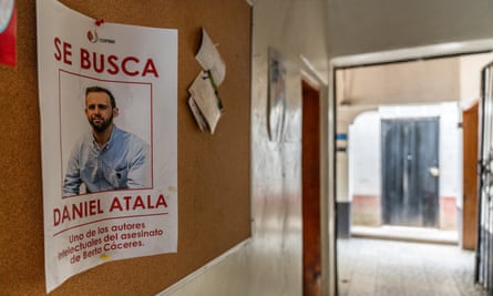 A poster on a hallway wall of a man in a formal shirt saying ‘se busca’ (wanted) and Daniel Atala, above a line saying he is one of the authors of the assassination of Berta Cáceres