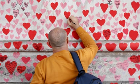 A man writes a message on the national Covid memorial wall on the South Bank in London