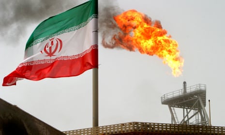 A gas flare on an oil production platform, with an Iranian flag in the foreground