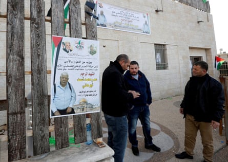 Men stand next to a poster featuring the illustration of a man