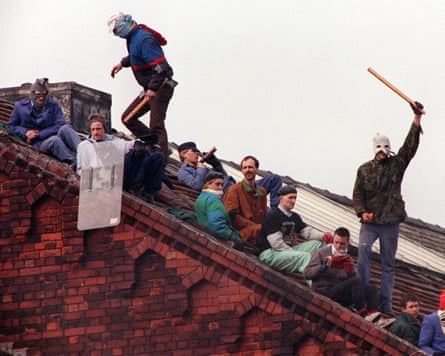 Men, some in homemade balaclavas, on the roof of a red brick building