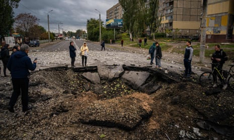 Local residents examine a crater following a missile strike in Dnipro on 10 October 2022, amid Russia's invasion of Ukraine.