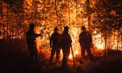 The silhouette of firefighters against a backdrop of burning trees.