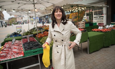 woman in a beige raincoat in front of some market stalls