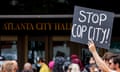 a person holds a sign that reads 'stop cop city'